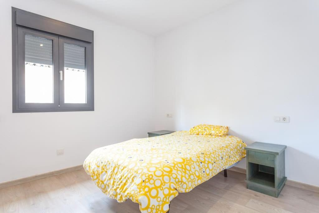 1 dormitorio con 1 cama con colcha amarilla y ventana en Quite and brightly single room. en Sa Pobla