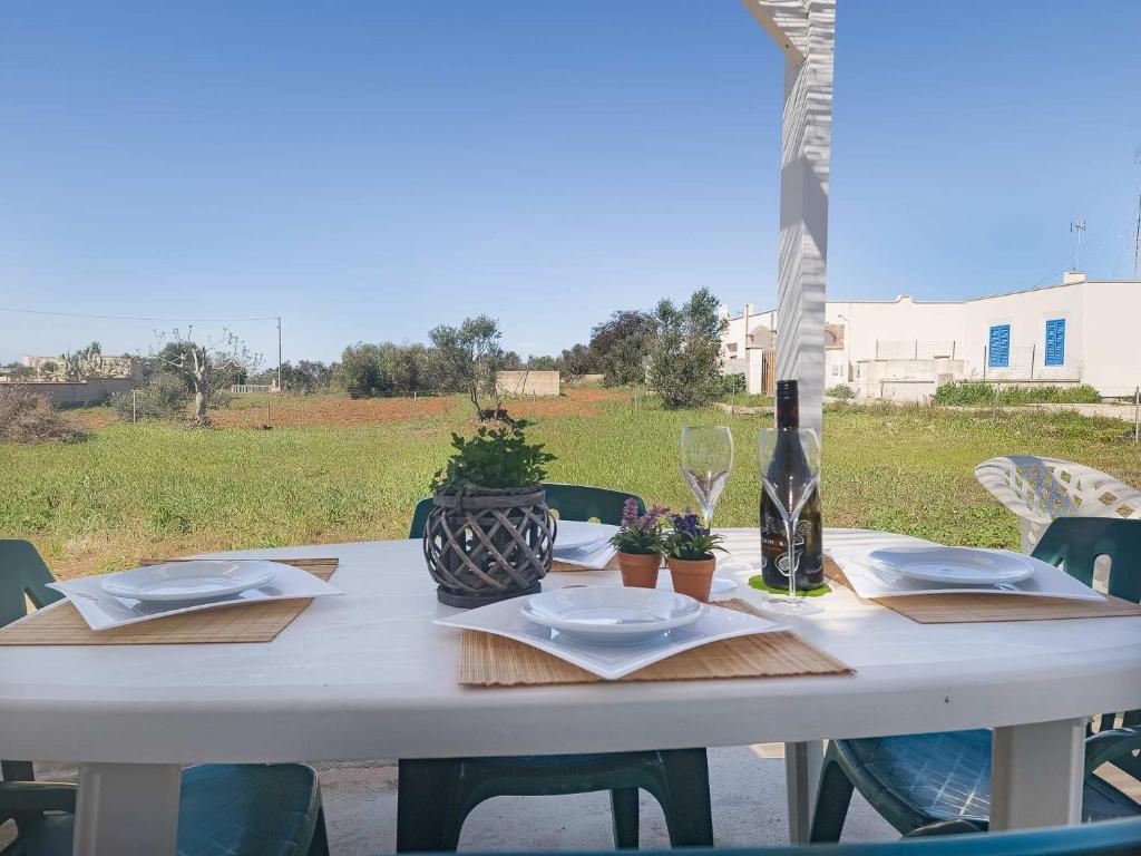 Villetta Gioia في توري سودا: طاولة بيضاء مع أطباق وزجاجة من النبيذ