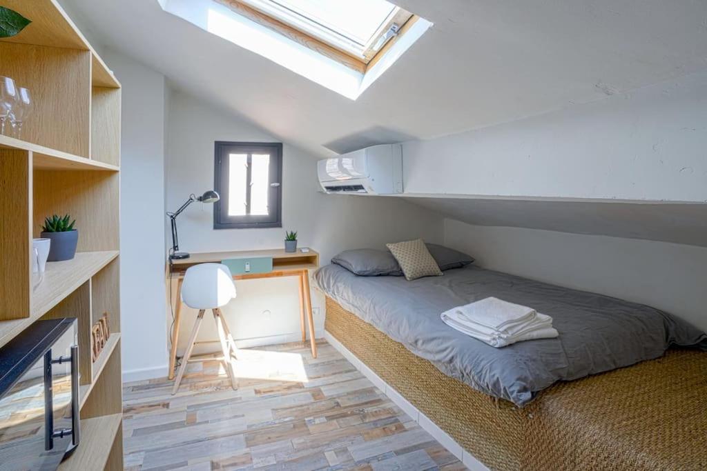une chambre avec un lit, un bureau et une fenêtre dans l'établissement Studio sous les toits très bien placé et climatisé, à Montpellier