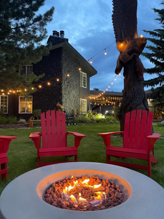a fire pit in a yard with two chairs and a statue at Chalet Inn in Whitefish