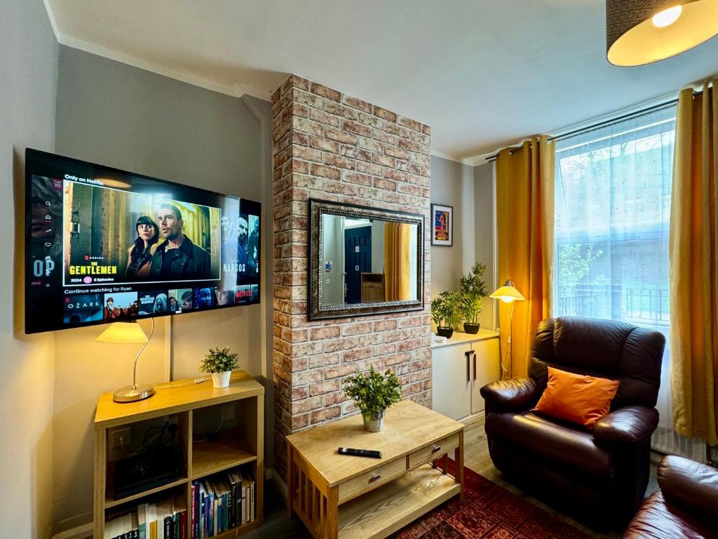 a living room with a couch and a fireplace with a tv at Waterloo House - Urban Oasis Townhouse in Nottingham
