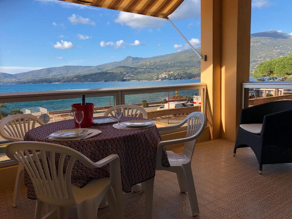 een tafel en stoelen op een balkon met uitzicht op de oceaan bij Grand F1 face à la plage, Climatisé, parking, grand confort 4 pers in Propriano