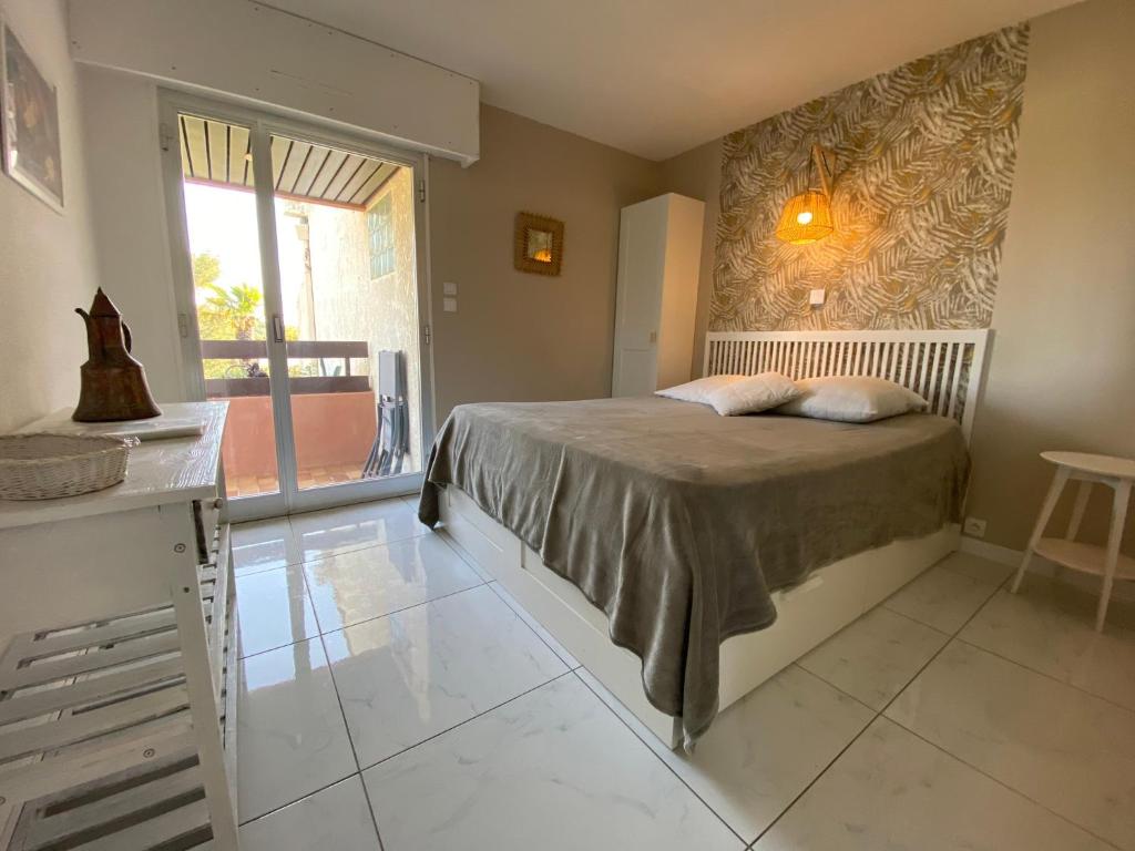 een slaapkamer met een bed en een groot raam bij Appartement Cosy à Sanary Plage de Portissol-Climatisé-Parking privé in Sanary-sur-Mer