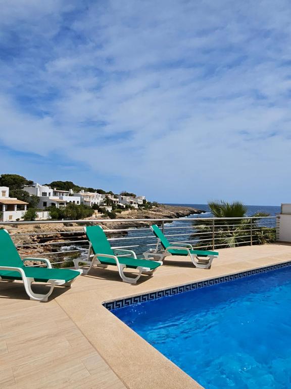 um grupo de cadeiras sentadas ao lado de uma piscina em Casa Voramar em Cala d´Or