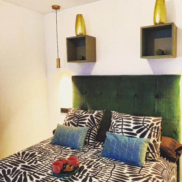 a bed with a green headboard and some pillows at El Rincón de Eva II in Salamanca