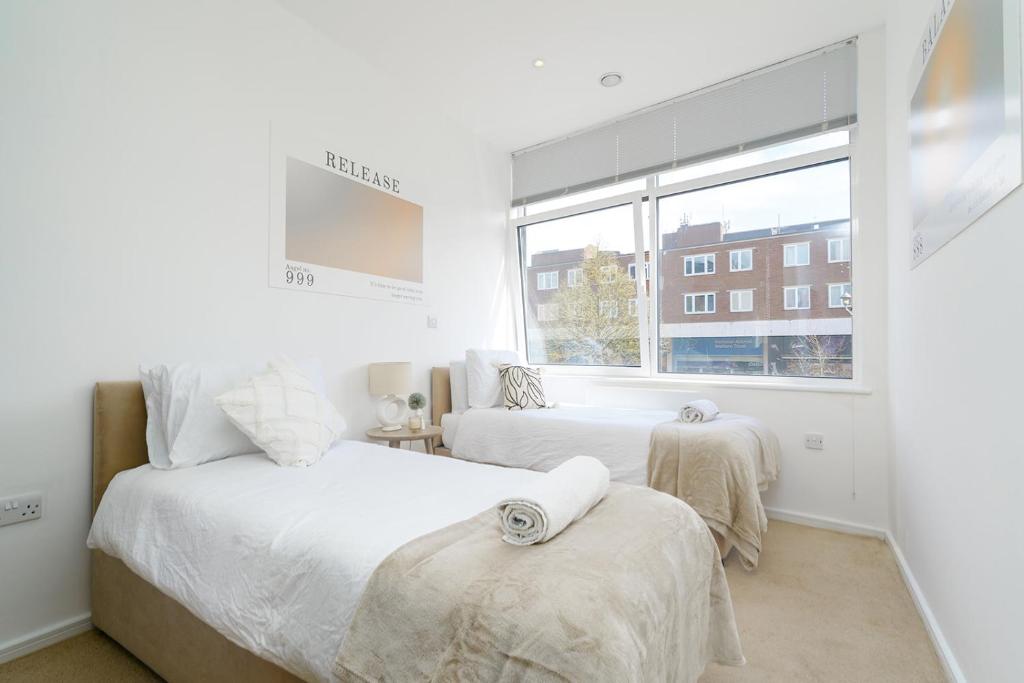 um quarto branco com 2 camas e uma janela em Brightway Hemel, WiFi and Netflix, Perfect for Contractors and Relocators em Hemel Hempstead