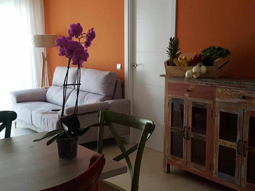 un salon avec une table et un vase de fleurs violettes dans l'établissement Mandala apARTments, à Calafell