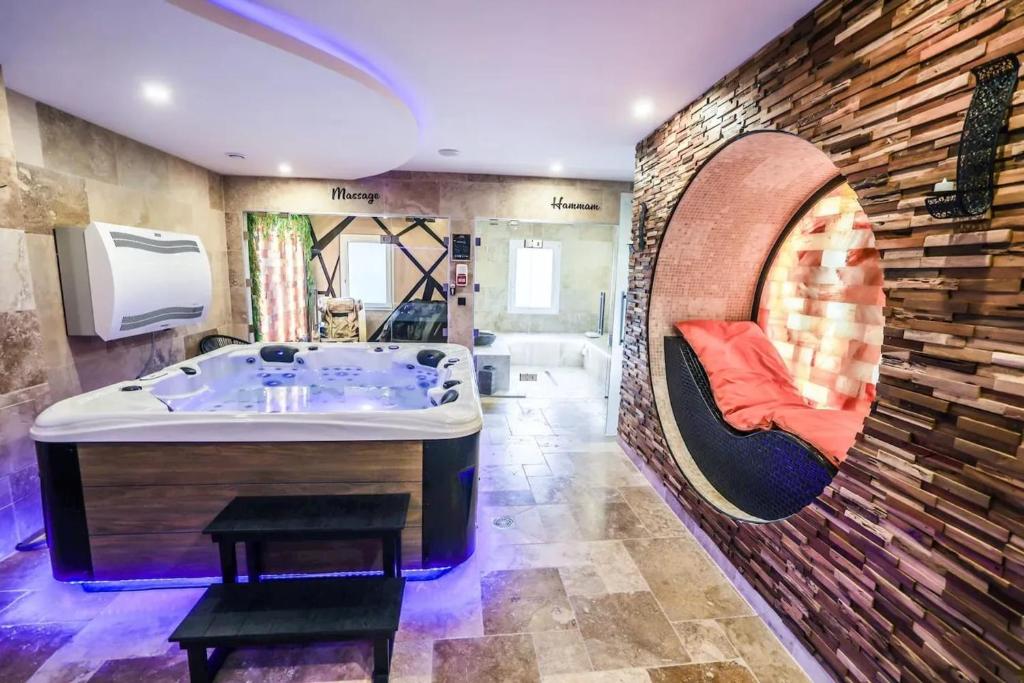 ein Badezimmer mit einer großen Badewanne in einer Ziegelwand in der Unterkunft Appartement d'une chambre avec piscine privee sauna et wifi a Montbeliard in Montbéliard