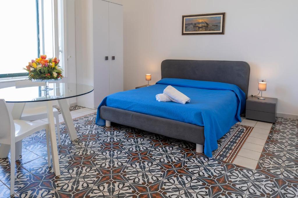a bedroom with a blue bed and a table at Le Suite del Castello in Castellammare di Stabia