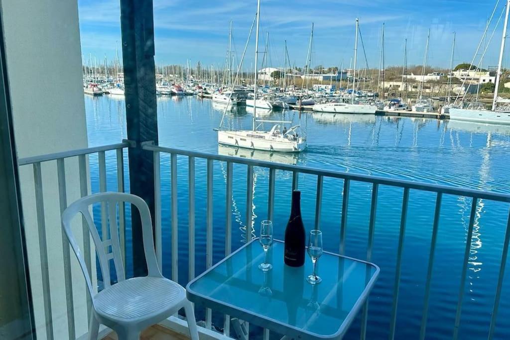 einen Glastisch und eine Flasche Wein auf dem Balkon in der Unterkunft Appartement ensoleillé au Cap d'Agde in Cap d'Agde