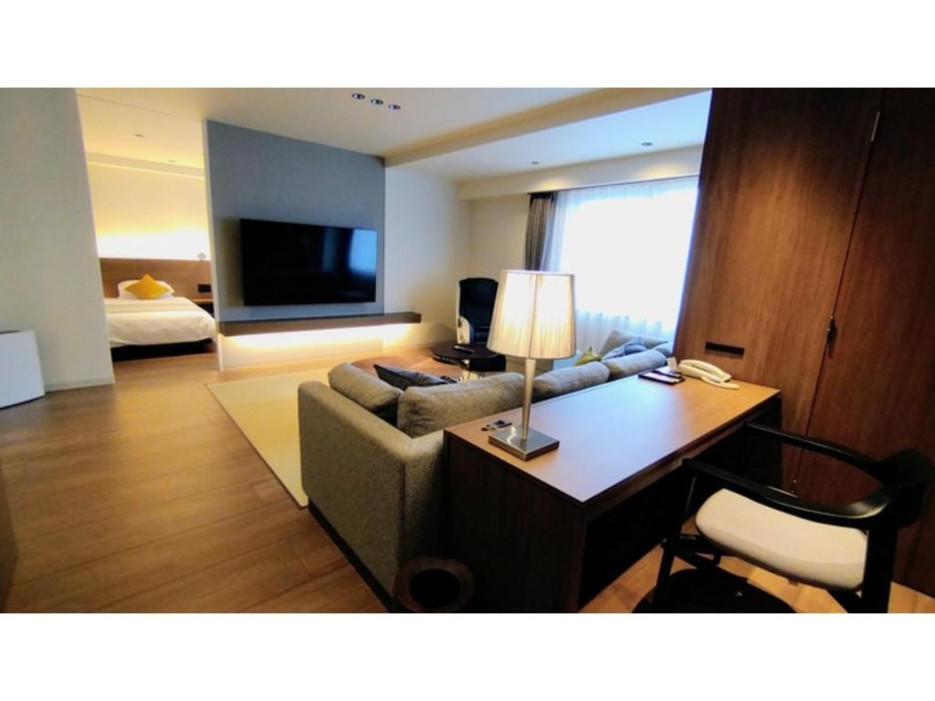 ein Wohnzimmer mit einem Sofa und einem Schreibtisch mit einer Lampe in der Unterkunft Rishiri Fuji Kanko Hotel - Vacation STAY 63401v in Oshidomari