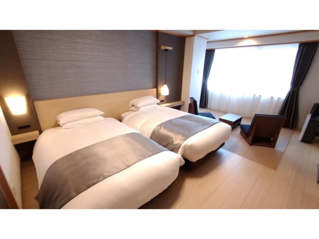 three beds in a hotel room with a window at Rishiri Fuji Kanko Hotel - Vacation STAY 63411v in Oshidomari
