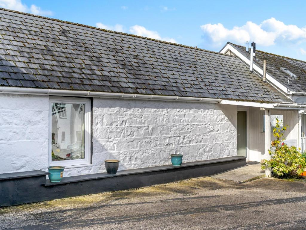 a white house with two blue pots on a window at 1 Bed in Newton Stewart DF198 in Newton Stewart