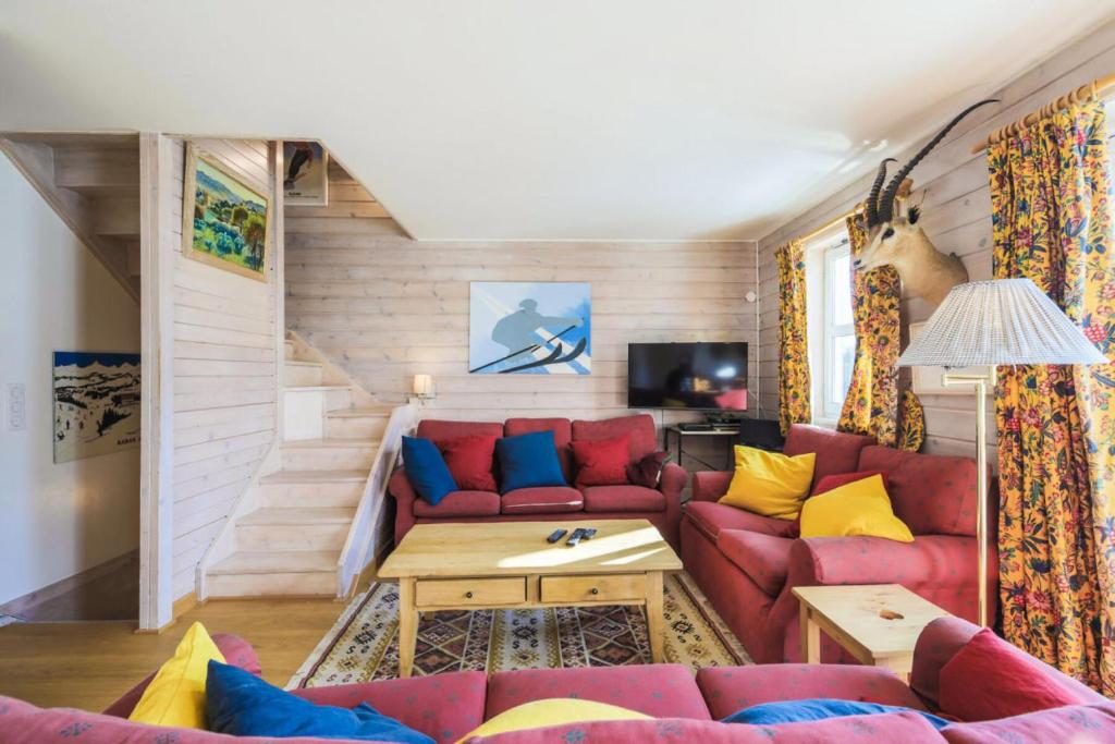 un salon avec un canapé rouge et des coussins jaunes et bleus dans l'établissement Les Chalets de Flaine Hameau - maeva Home - Chalet 7 Pièces 12 Personnes - Sélection MAE-3656, à Flaine