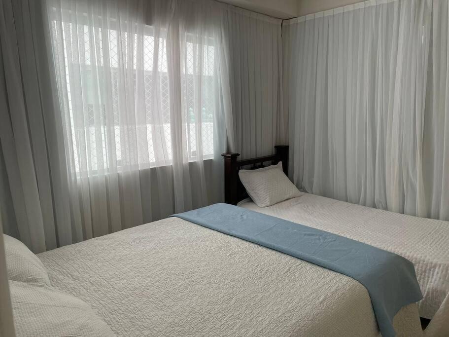 1 Schlafzimmer mit 2 Betten und einem Fenster mit Vorhängen in der Unterkunft Condomínio na praia em Nísia Floresta - Tabatinga - Natal/RN in Nísia Floresta