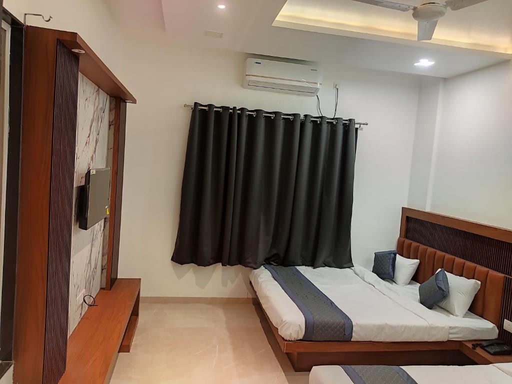 um quarto com uma cama e uma cortina preta em Hotel Nandan em Shegaon