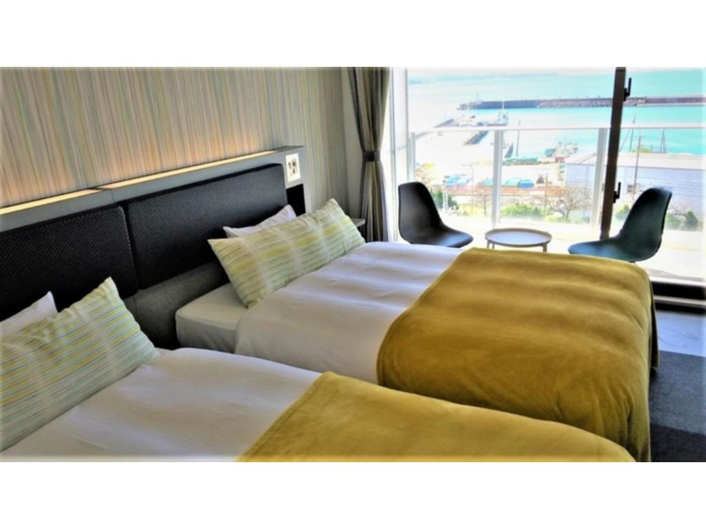 Green Rich Hotel Okinawa Nago - Vacation STAY 49889v في ناغُو: غرفة فندقية بسريرين ونافذة