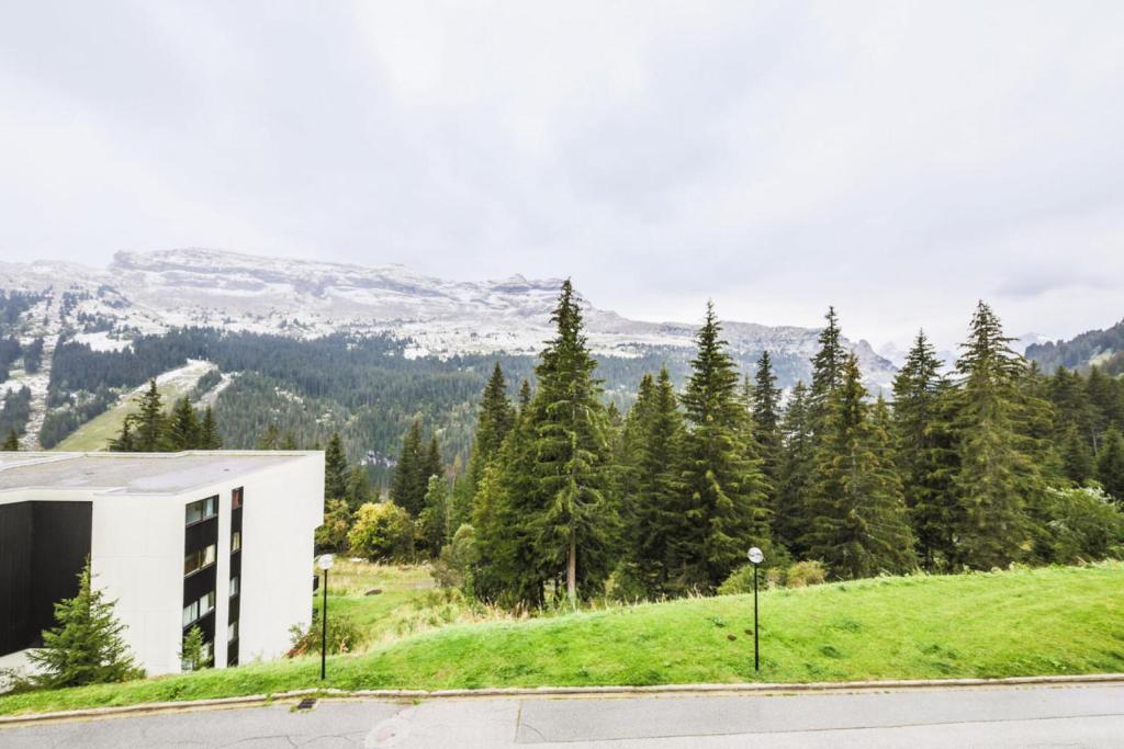 un bâtiment sur le côté d'une colline plantée d'arbres dans l'établissement Résidence Arche - maeva Home - Appartement 2 Pièces 6 Personnes - Confort MAE-3694, à Arâches-la-Frasse
