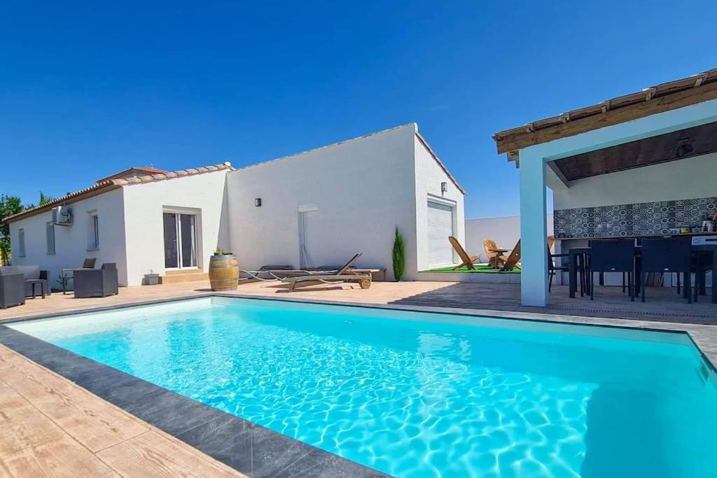 une villa avec une piscine en face d'une maison dans l'établissement Villa 3 chambres avec piscine, à Saint-Laurent-dʼAigouze