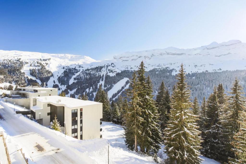 un bâtiment au sommet d'une montagne enneigée avec des arbres dans l'établissement Résidence Arche - maeva Home - Studio 4 Personnes - Confort MAE-3695, à Arâches-la-Frasse