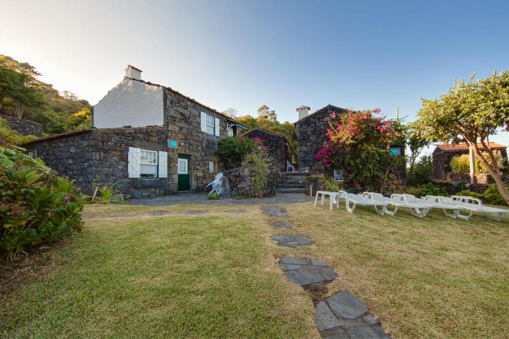 a stone house with white benches in front of it at Casas de Campo HousesInPico in Prainha de Baixo