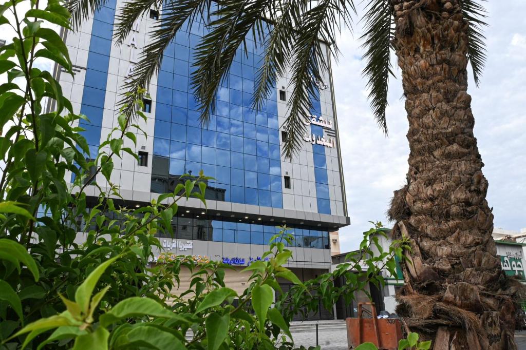 un edificio con una palmera delante de él en بيوت ملاذ للشقق الفندقية en Yeda