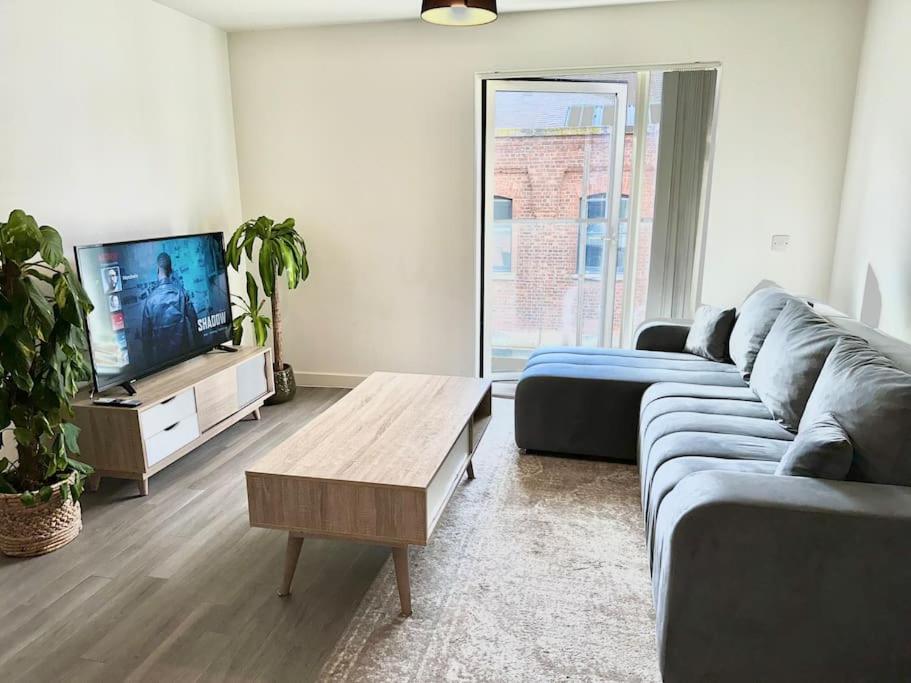 ein Wohnzimmer mit einem blauen Sofa und einem TV in der Unterkunft Luxury Central Manchester Apartment with Secure Parking in Manchester