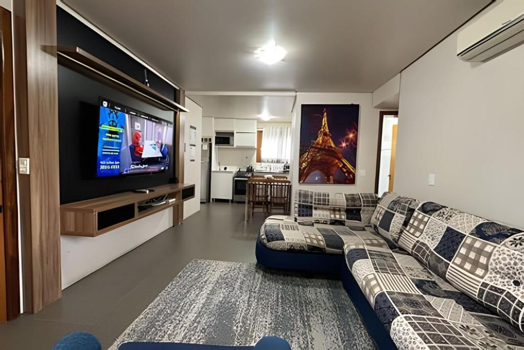 sala de estar con sofá y TV de pantalla plana en Apartamento Coração de Gramado, en Gramado