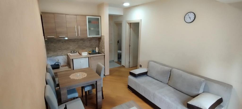 ein Wohnzimmer mit einem Sofa, einem Tisch und einer Uhr in der Unterkunft Apartman Miletić 4 in Zlatibor