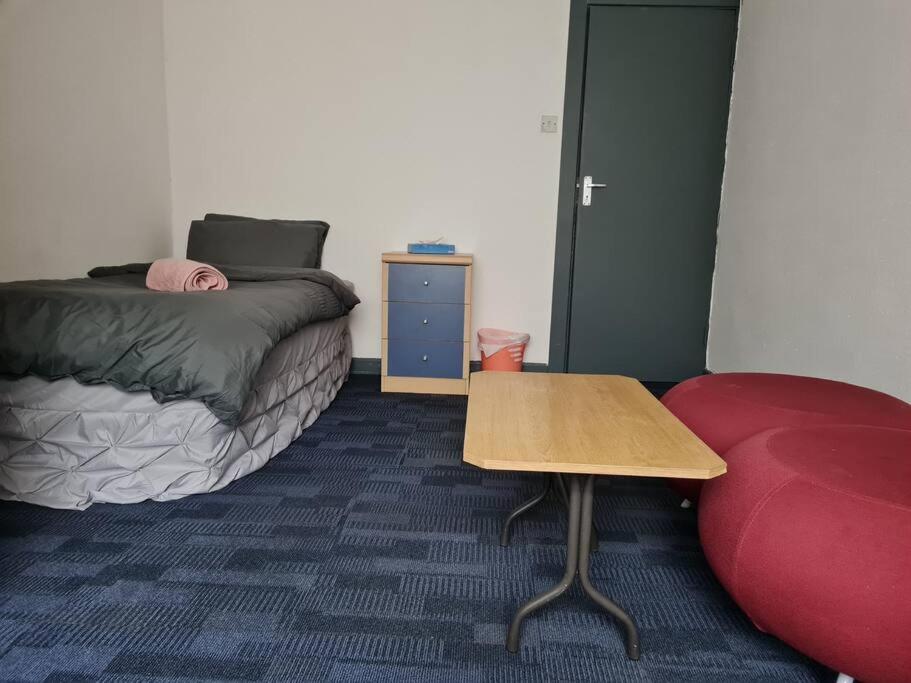 a room with a bed and a table and a red couch at Room near East Midland Airport Room 7 in Kegworth
