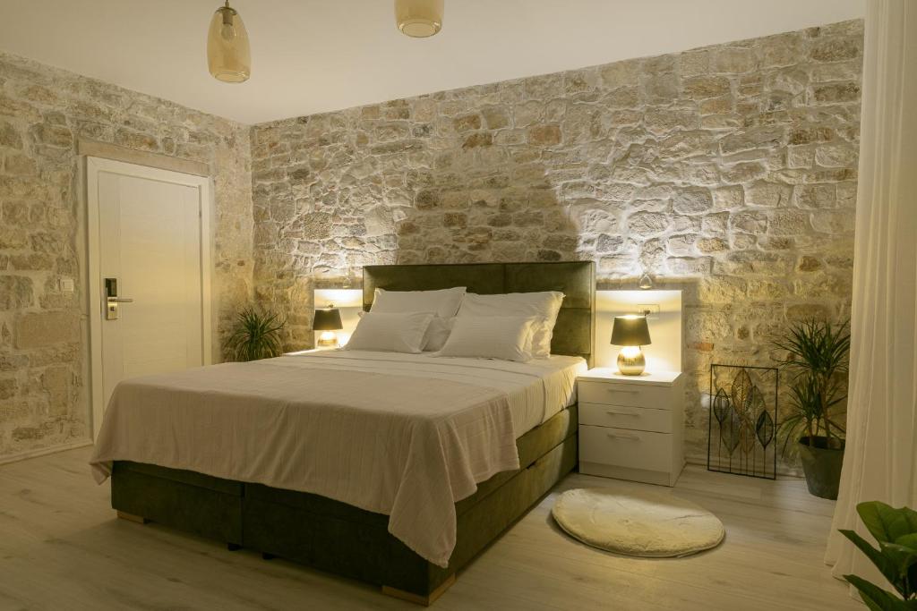 a bedroom with a bed and a stone wall at Sobe Bartul Trogir in Trogir