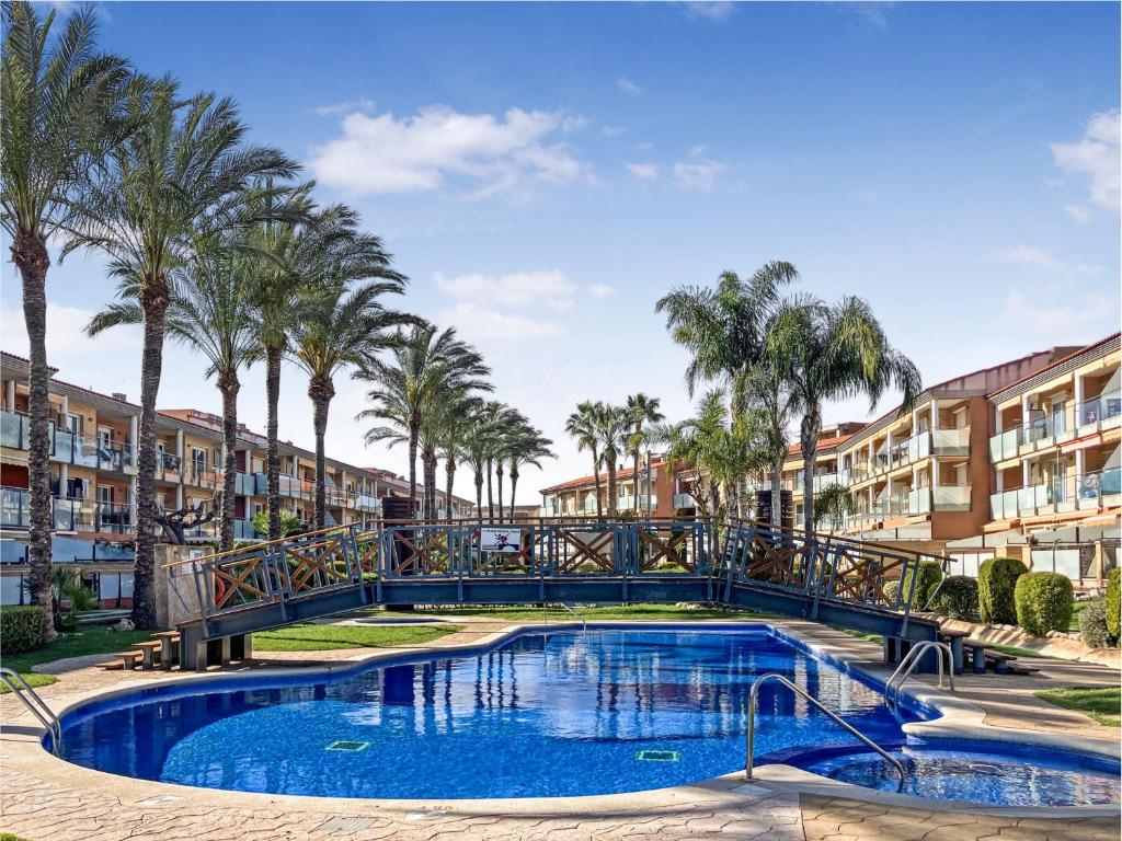 a pool with palm trees and apartment buildings at Apartamento Port Marino in Cambrils