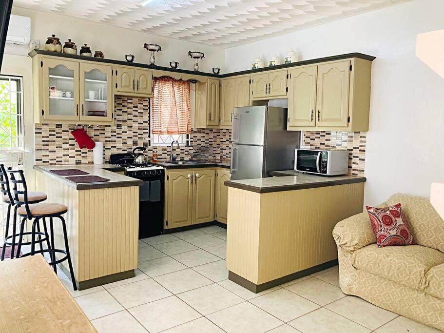 a kitchen with a refrigerator and a stove top oven at 1-bedroom suburban apartment with free parking in Kingstown