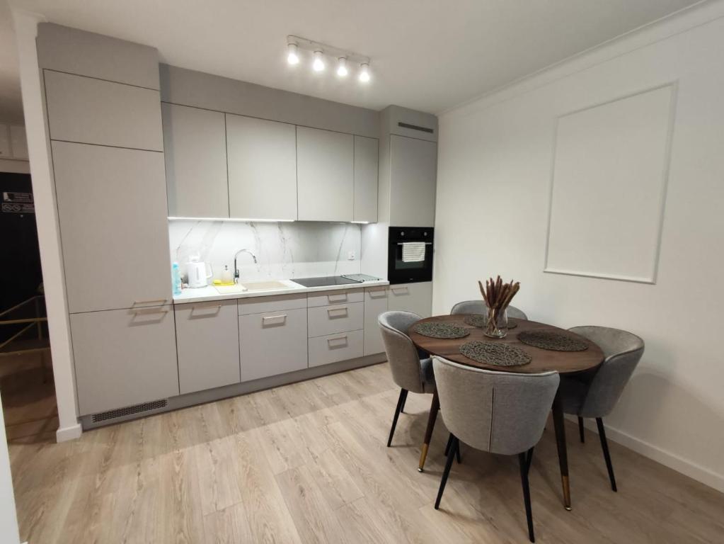 a kitchen with white cabinets and a table and chairs at STARCO Apartamenty Centrum in Stargard