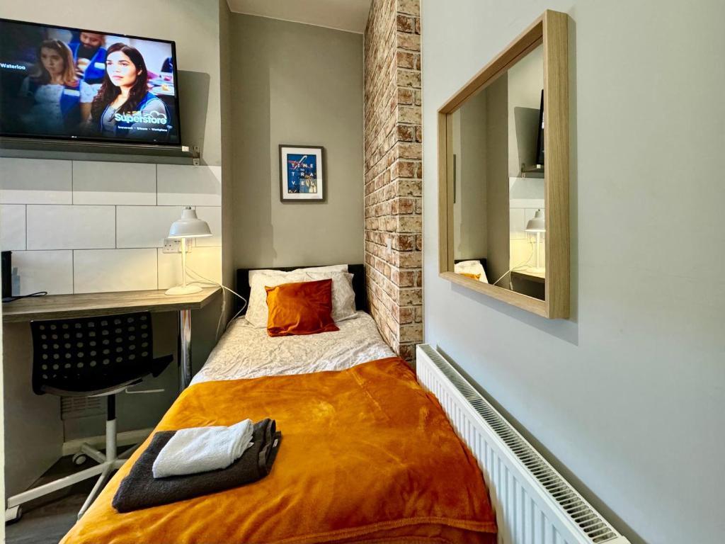 Cette petite chambre dispose d'un lit et d'une télévision murale. dans l'établissement Limpenny Studio - Cityscape Cozy Corner, à Nottingham