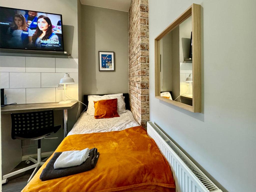 a small bedroom with a bed with a tv on the wall at Limpenny Studio - Cityscape Cozy Corner in Nottingham