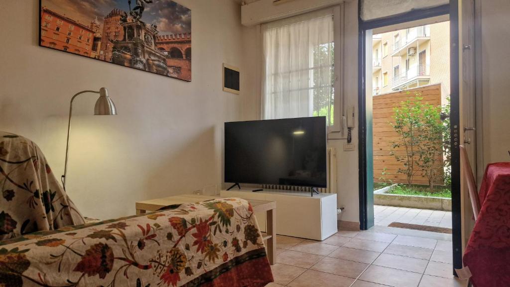 Una sala de estar con televisión y un sofá. en Fiorilli House - Fair District - Gratis Private Parking, en Bolonia