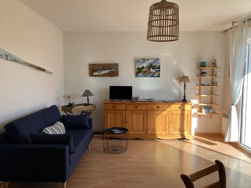 un salon avec un canapé bleu et une télévision dans l'établissement Sainte-Marine, Appartement cosy rez-de-jardin à 150m de la plage, à Combrit