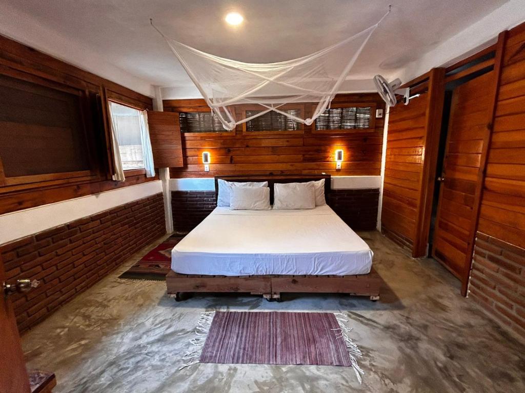 um quarto com uma cama num quarto com paredes de madeira em Casa Gaviota em Mazunte