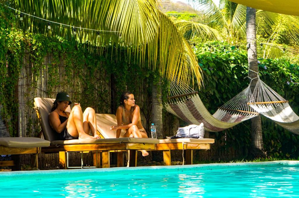 three women sitting in a hammock next to a pool at Casaola Mizata in Santa María Mizata