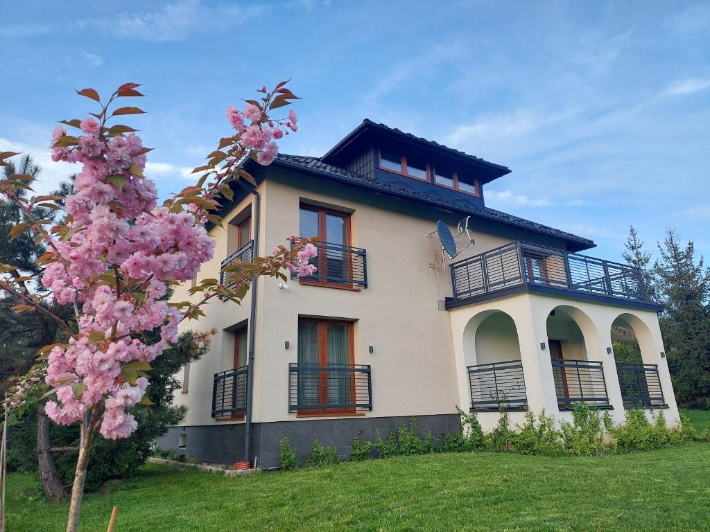 a house with a flowering tree in front of it at Apartamenty Brenna Klimorówka in Brenna