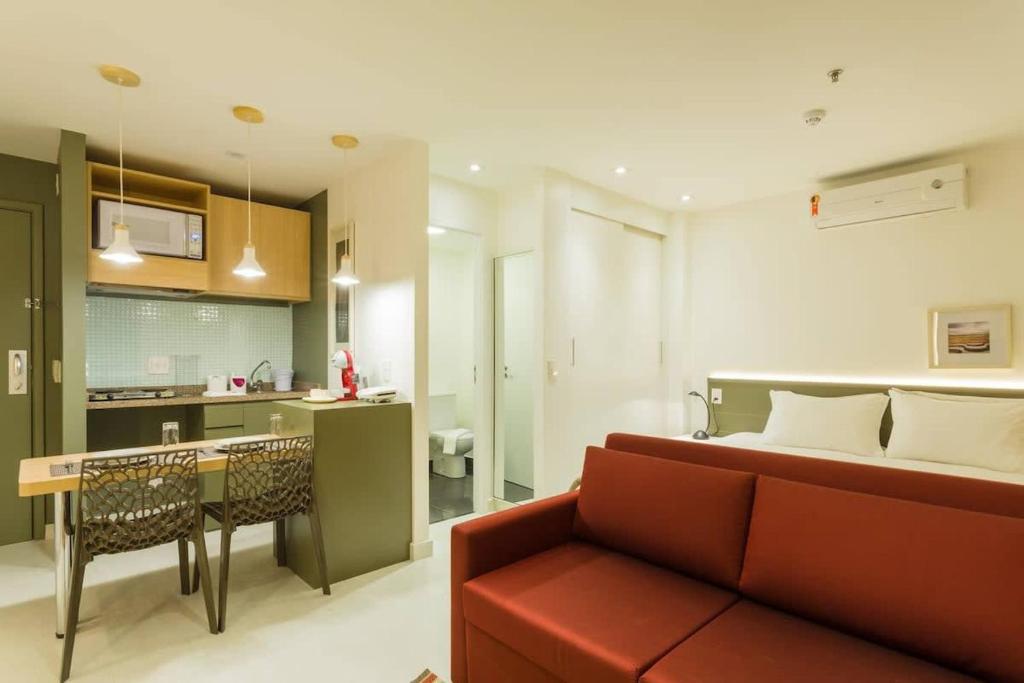 BHomy Jardins Requinte e conforto CE1510 في ساو باولو: غرفة معيشة مع أريكة حمراء ومطبخ