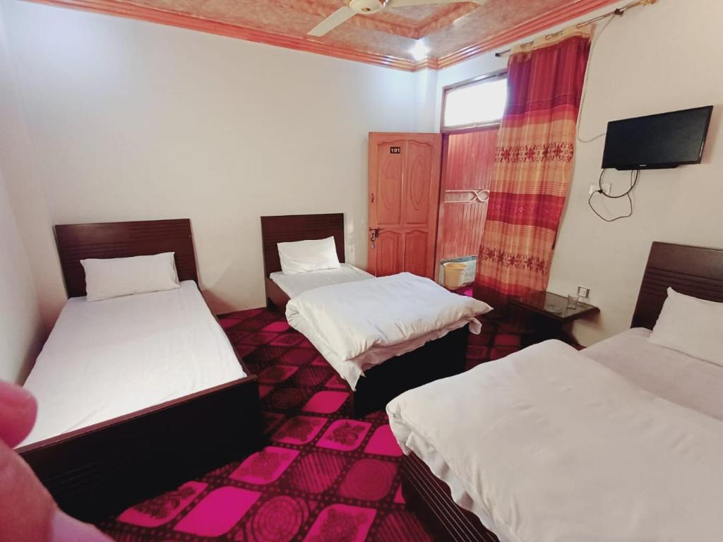 a room with three beds and a tv in it at Stay Inn Hotel in Mingāora