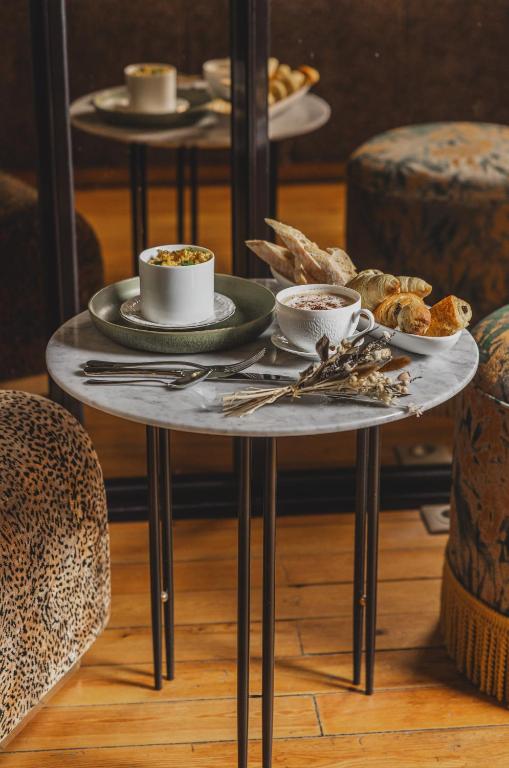 a table with cups and plates of food on it at Hôtel Singulier Bordeaux - Boutique Hôtel & Spa Anne Semonin in Bordeaux