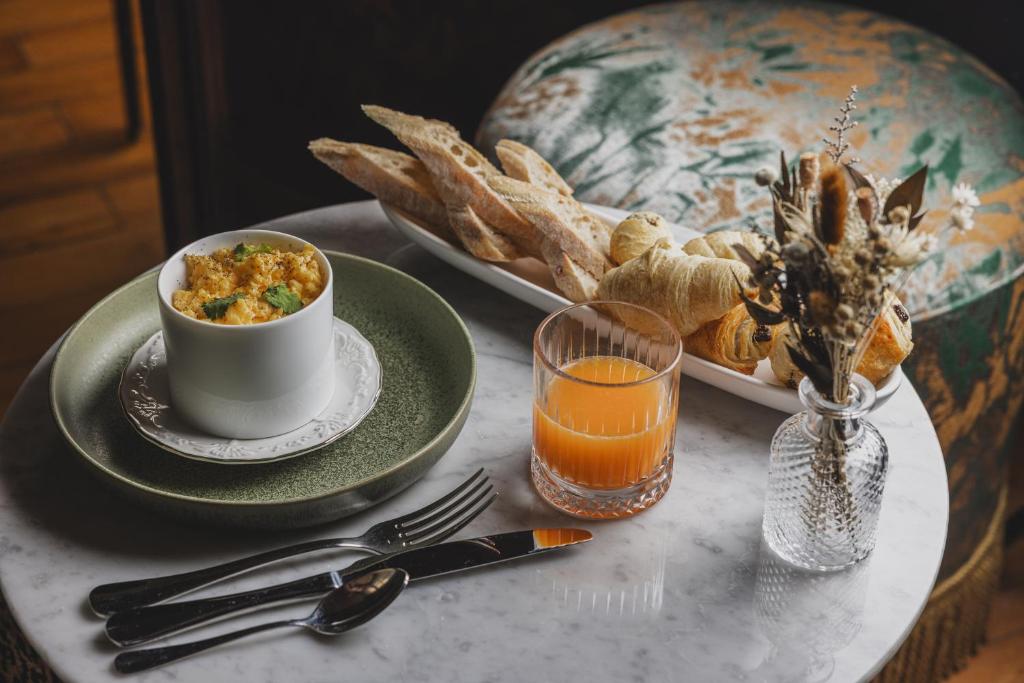 a table with a bowl of food and a plate of orange juice at Hôtel Singulier Bordeaux - Boutique Hôtel & Spa Anne Semonin in Bordeaux