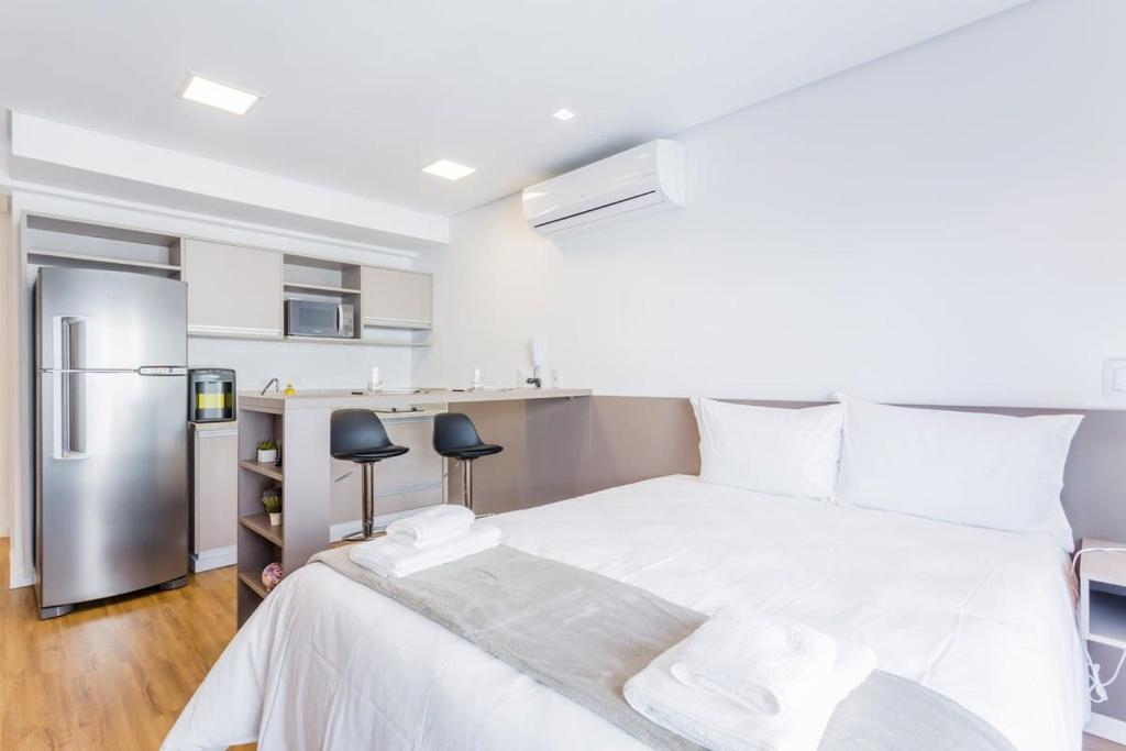 Schlafzimmer mit einem weißen Bett und einem Kühlschrank in der Unterkunft BHomy Bela Vista Completo e localização APM1204 in São Paulo