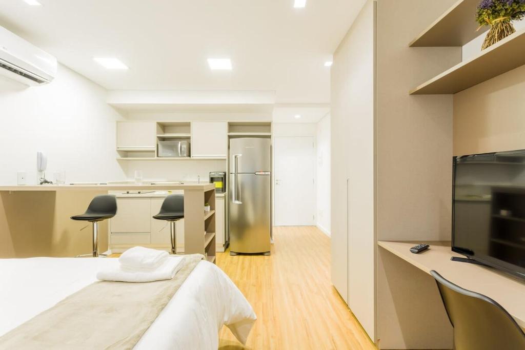 Zimmer mit einem Bett und einer Küche mit einem Kühlschrank. in der Unterkunft Studio redecorado no Bela Vista com Sacada e Lazer APM1205 in São Paulo