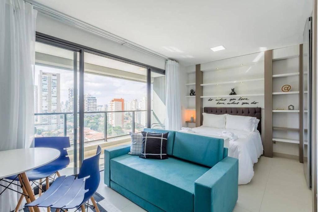 ein Schlafzimmer mit einem Bett und einem blauen Sofa in der Unterkunft BHomy Brooklin Moderno e com vista linda GB132B in São Paulo