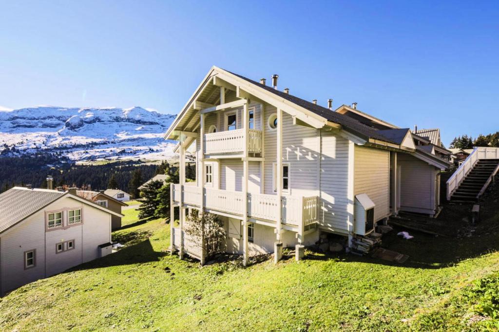 une maison assise au sommet d'une colline herbeuse dans l'établissement Les Chalets de Flaine Hameau - maeva Home - Chalet 5 Pièces 8 Personnes - Sélection MAE-2135, à Flaine