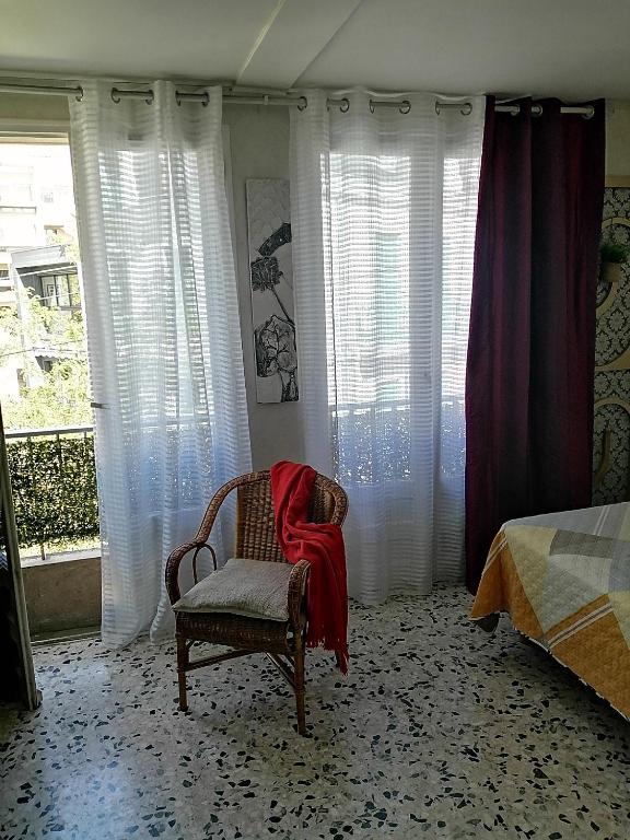 une chambre avec une chaise avec une couverture rouge dessus dans l'établissement Magnifique Studio non fumeur près de la gare, à Béziers